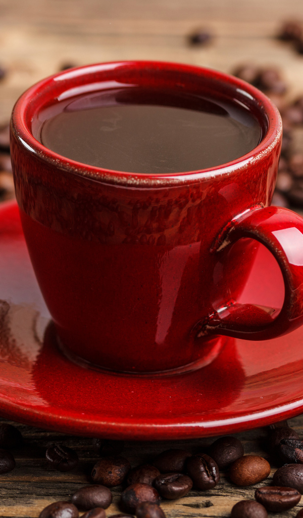 Красная чашка кофе на блюдце с кофейными зернами