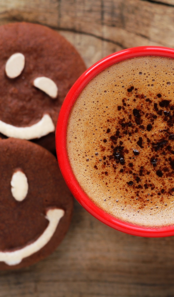 Красная чашка кофе с печеньем смайлами на столе