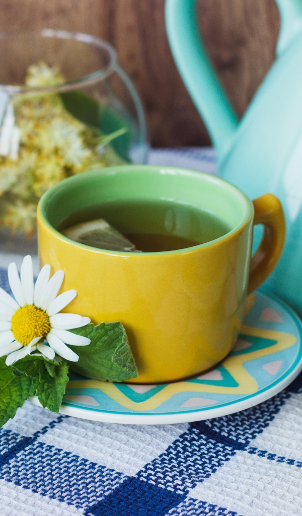 Чай с цветами ромашки в желтой чашке на столе