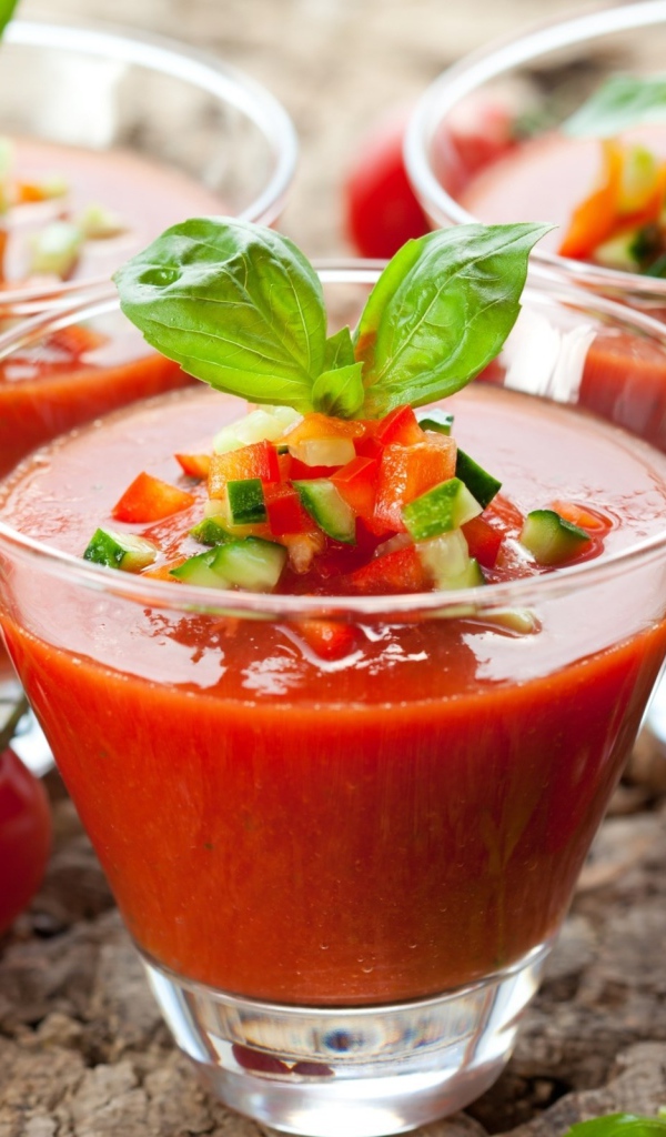 Три стакана томатного сока с овощами на столе