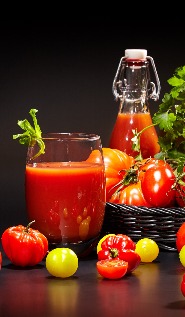 Томатный сок и свежие помидоры на столе на черном фоне