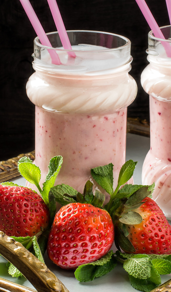 Два свежих клубничных коктейля с трубочками и ягодами клубники