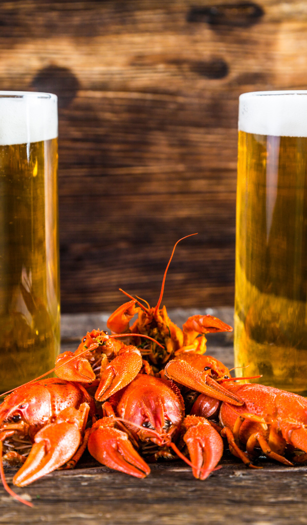Два бокала пива с красными раками на столе