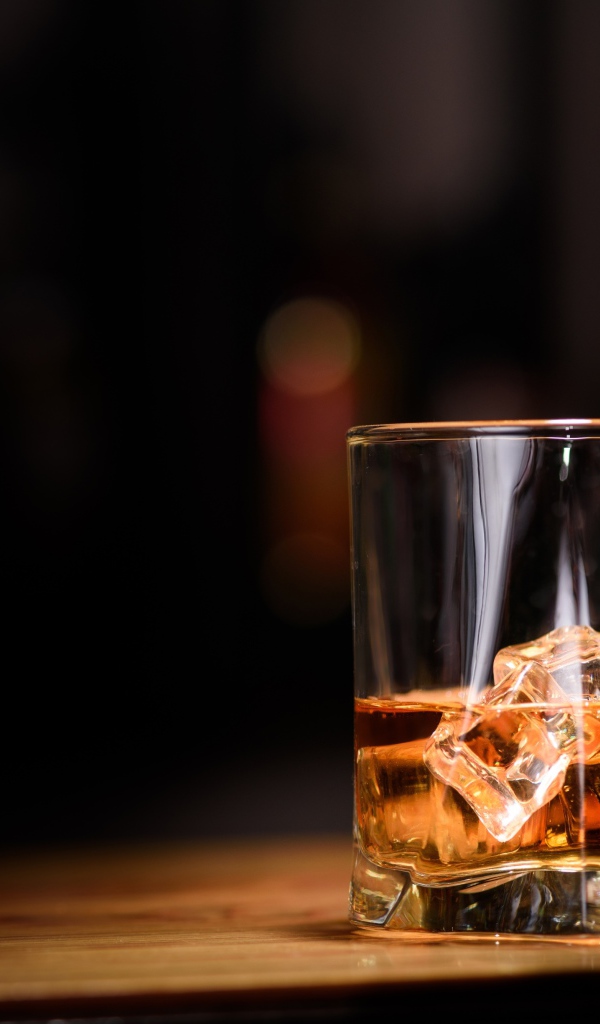 Виски наливают из бутылки в стакан со льдом