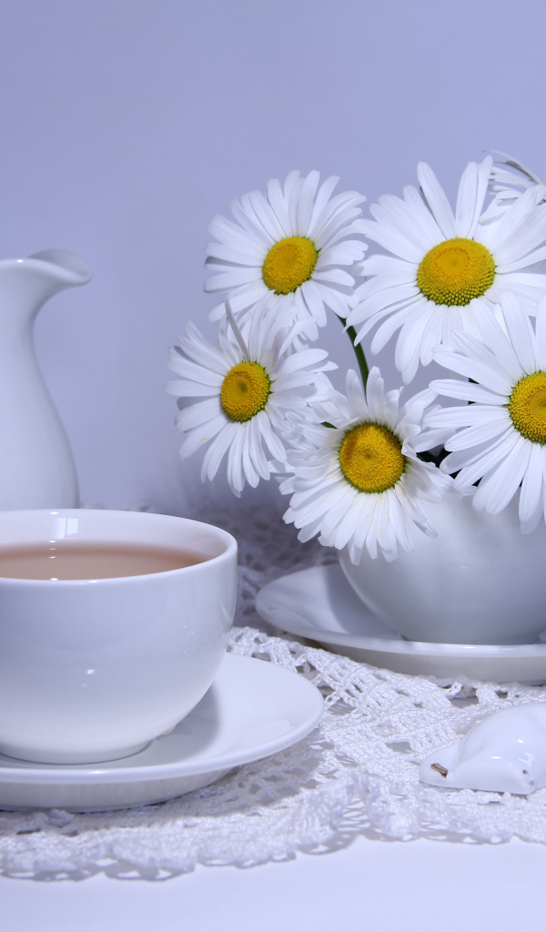 Белая чашка какао на столе с кувшином и белыми ромашками