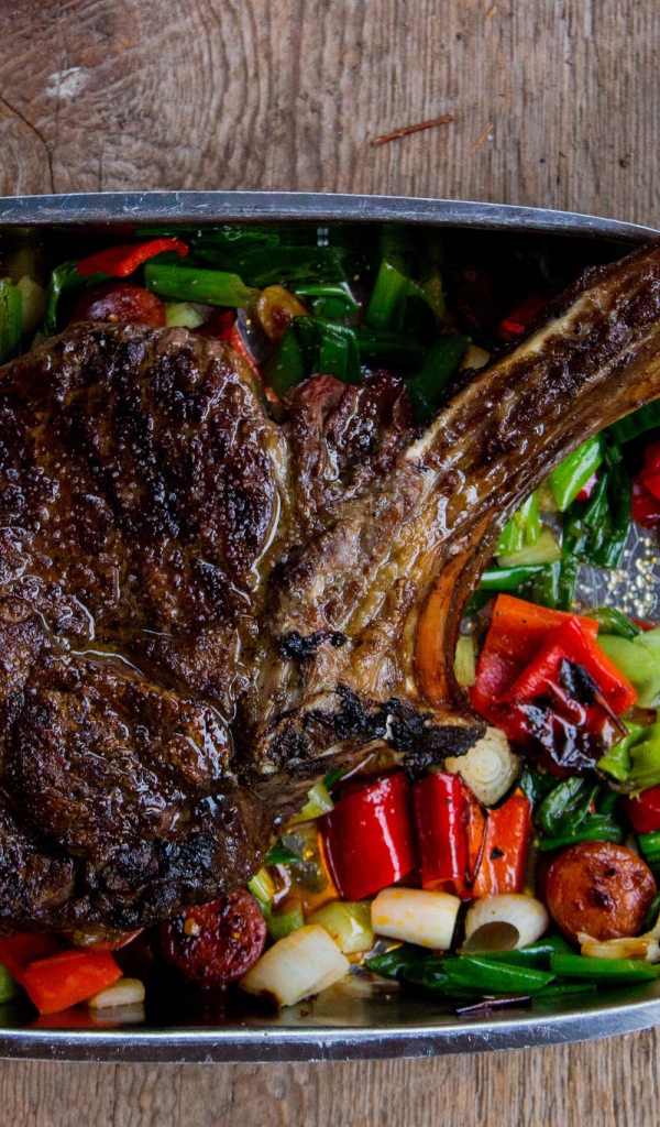 Кусок жареного мяса на ребрышке с овощами