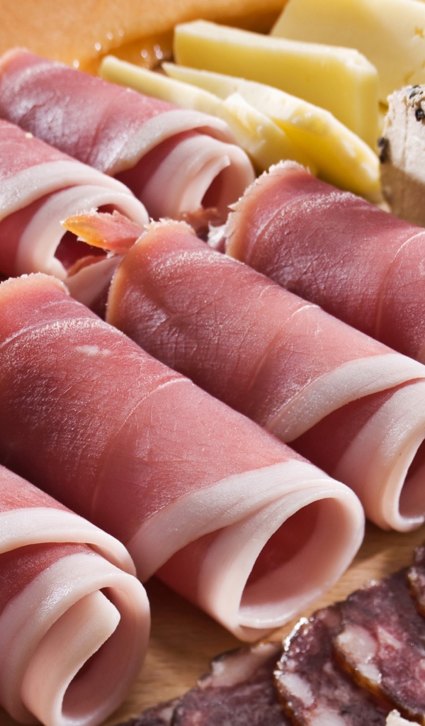 Аппетитные рулетики из бекона на тарелке с зелеными оливками