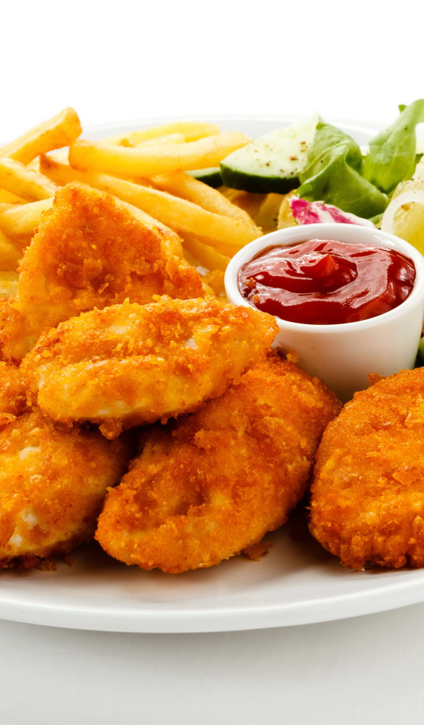 Куриные наггетсы с кетчупом, картофелем фри и салатом на белой тарелке