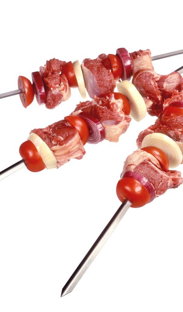 Мясо с овощами для шашлыка на шампурах на белом фоне