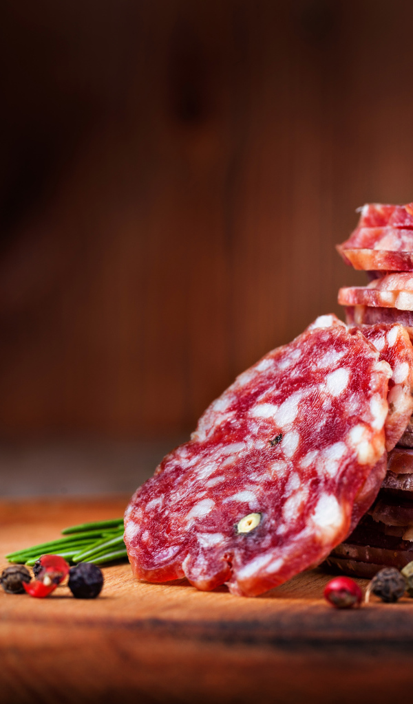 Нарезанная сухая колбаса на столе со специями