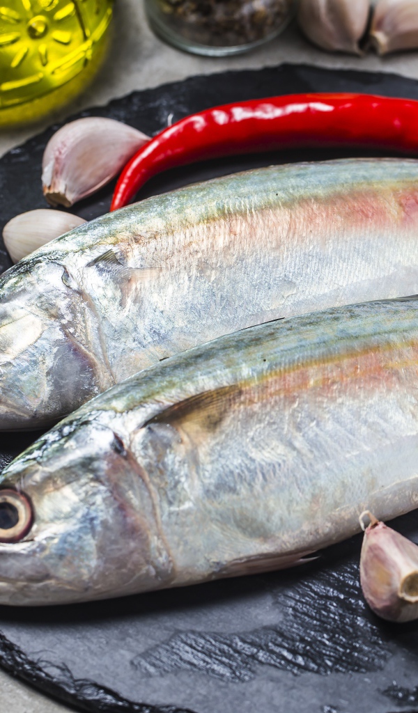 Свежая рыба на столе с красным перцем, чесноком и специями