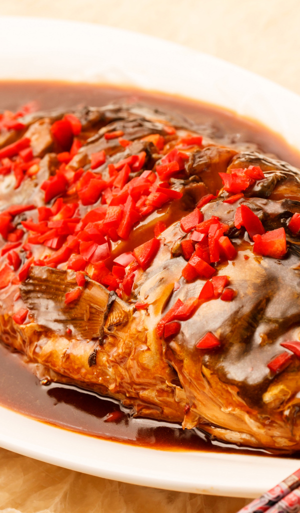 Жареная рыба с соусом и красным перцем в белом блюде