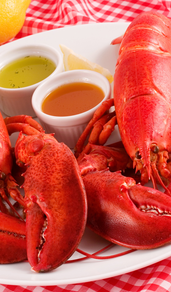 Два вареных омара на тарелке с соусом