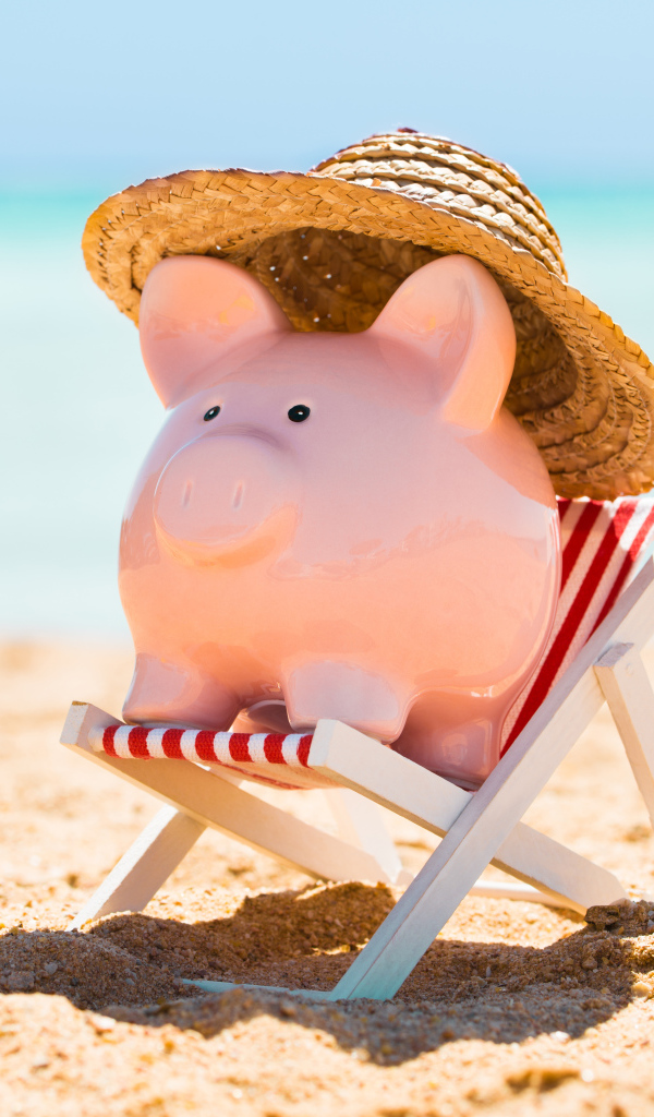 Souvenir piggy in hat lies in a toy chair on the beach