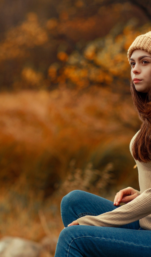 Молодая девушка в синих джинсах и теплой шапке