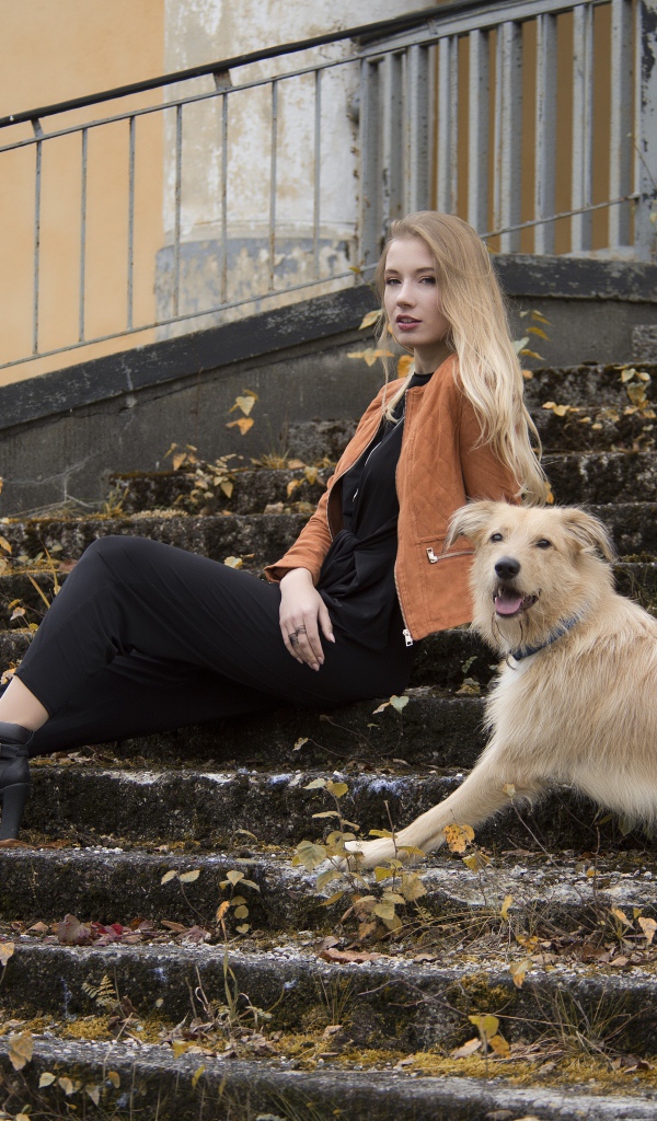 Молодая девушка сидит с собакой на старых ступеньках