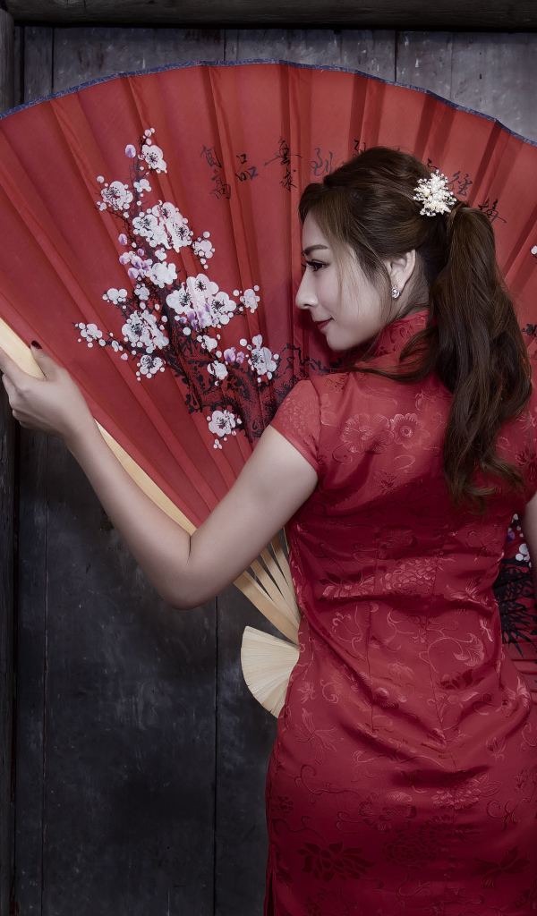 Красивая девушка азиатка в красном платье с большим веером