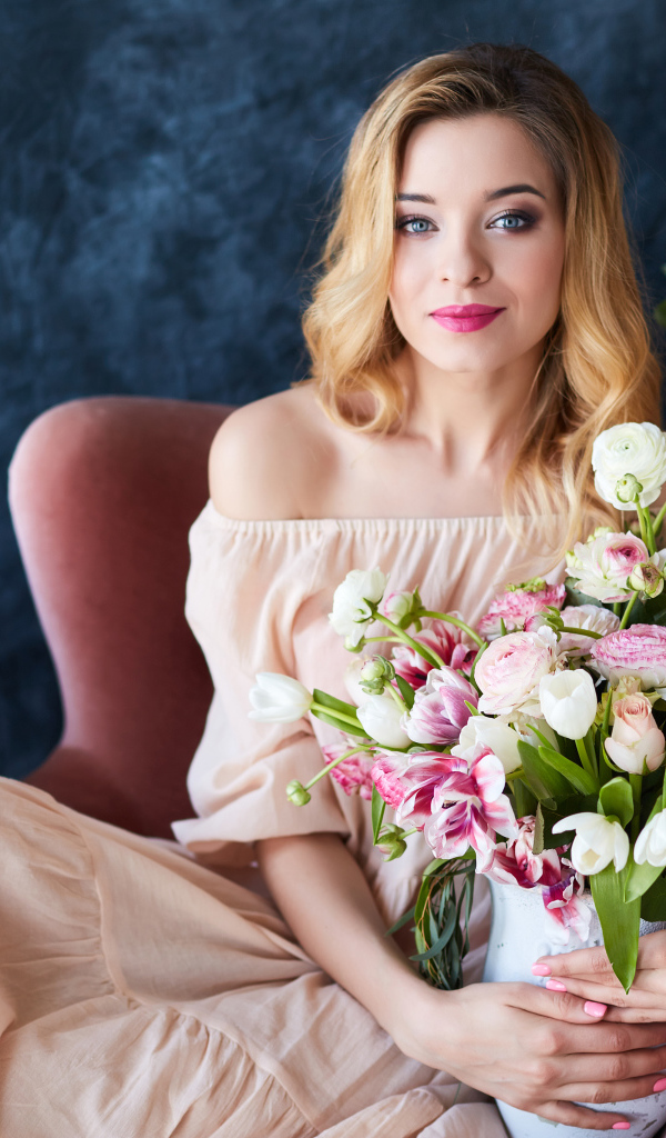 Красивая девушка блондинка сидит с букетом цветов