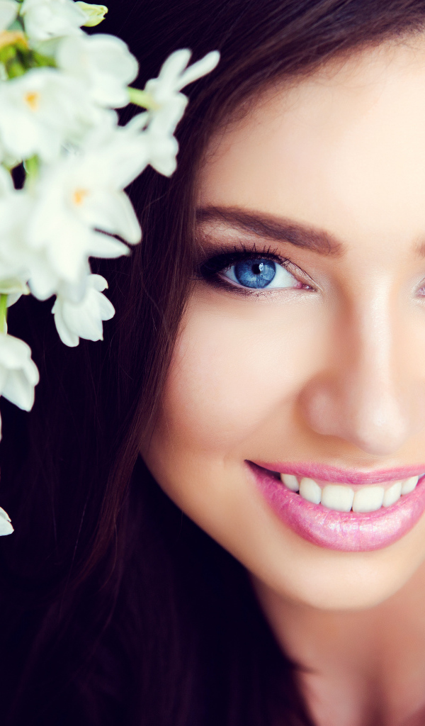 Красивая голубоглазая брюнетка с нежными цветами белой орхидеи