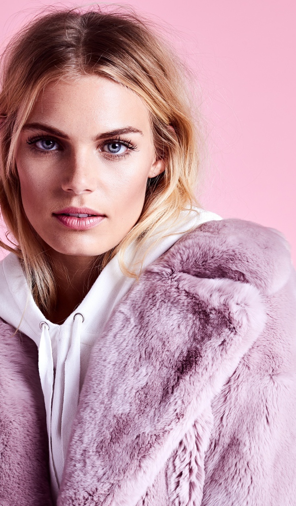 Красивая голубоглазая девушка в шубе на розовом фоне