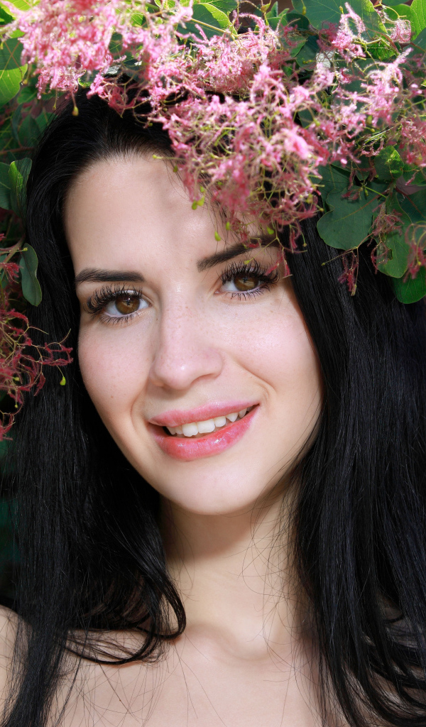 Красивая брюнетка стоит у цветущей ветки