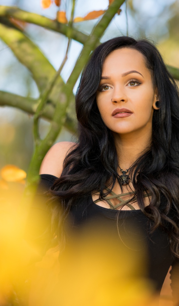 Красивая брюнетка у дерева в черном платье