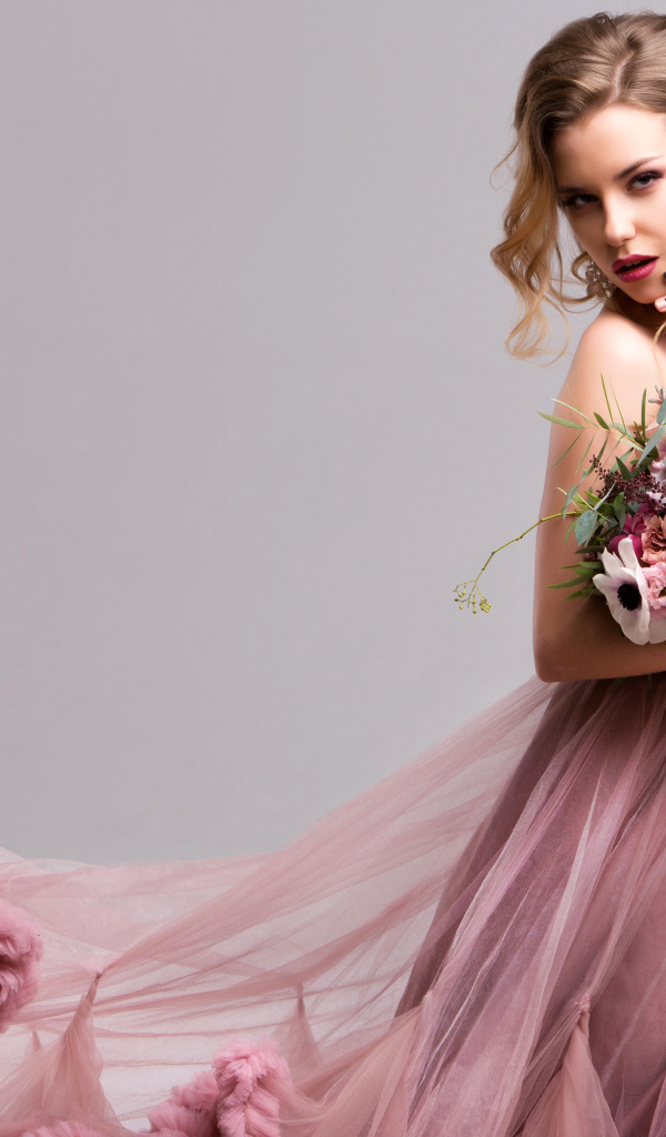 Эффектная девушка в красивом розовом платье с букетом цветов в руках