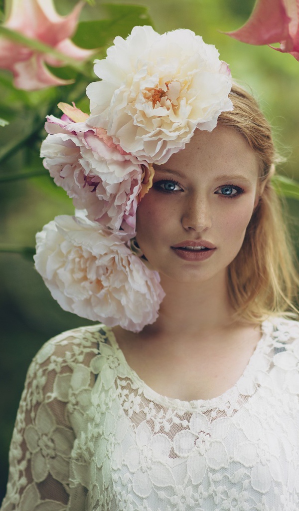 Красивая девушка в белом платье с большими пионами в волосах 
