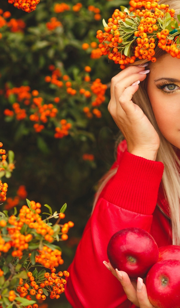Красивая девушка с венком из рябины на голове и с красными яблоками в руках 