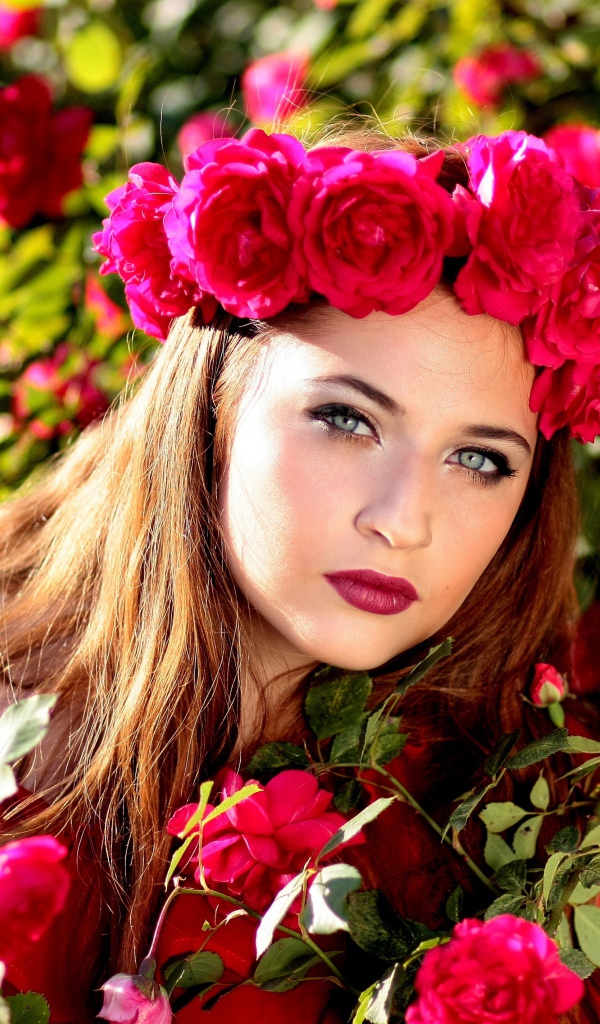 Красивая девушка с венком из красных роз на голове 
