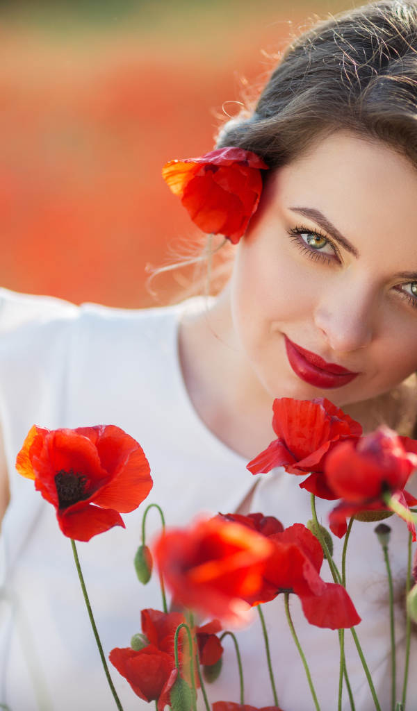 Красивая девушка с выразительным взглядом на поле с красными маками