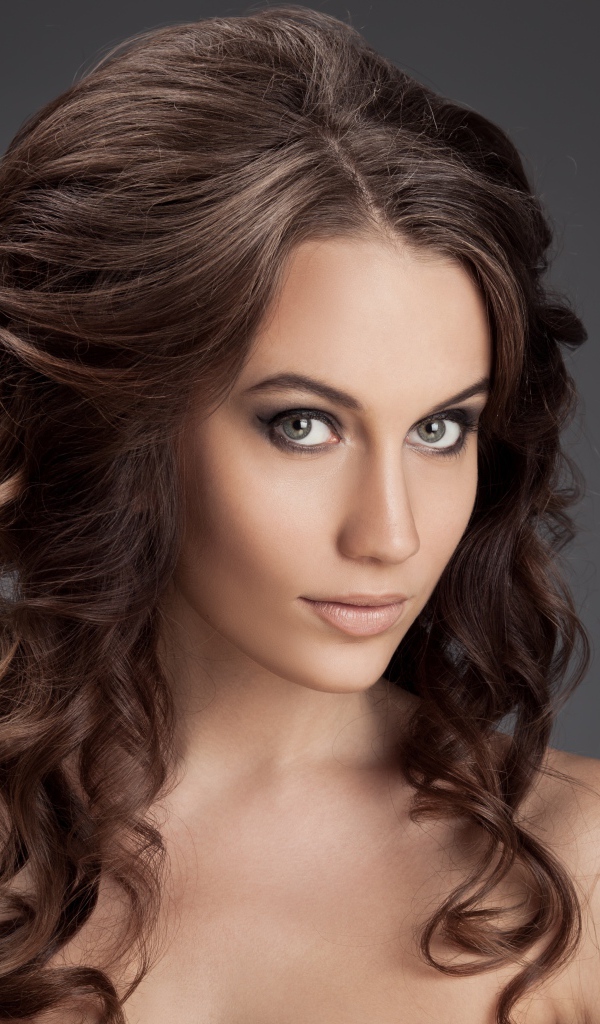 Красивая девушка с волнистыми волосами фото на сером фоне