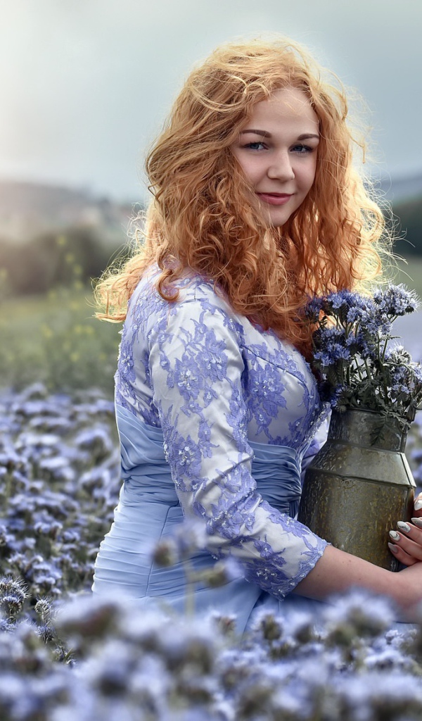 Красивая рыжеволосая девушка собирает цветы