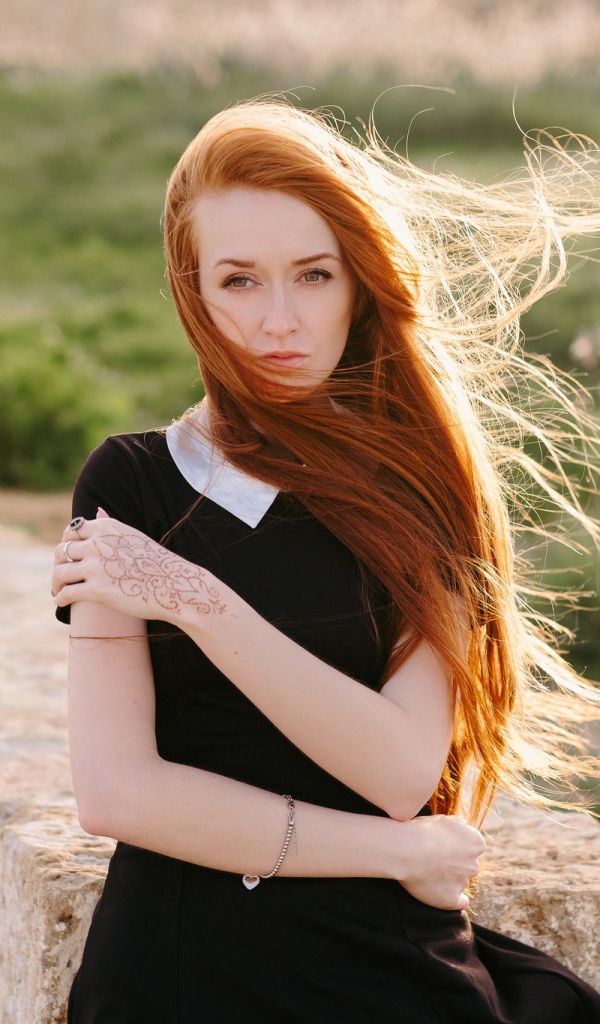 Красивая рыжеволосая девушка в черном платье с рисунком на руке