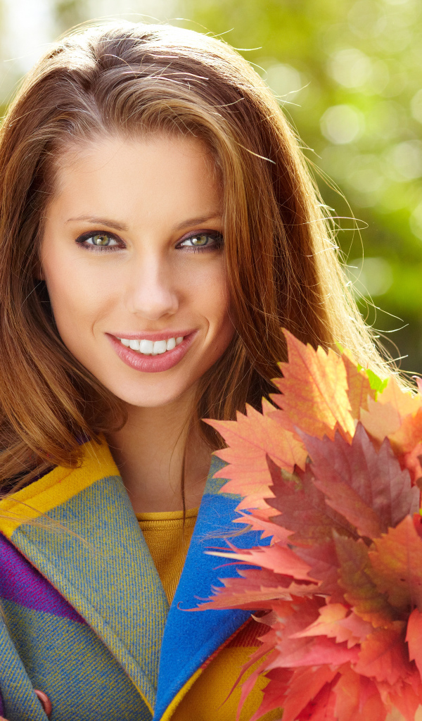 Красивая улыбающаяся девушка с букетом желтых листьев в руке