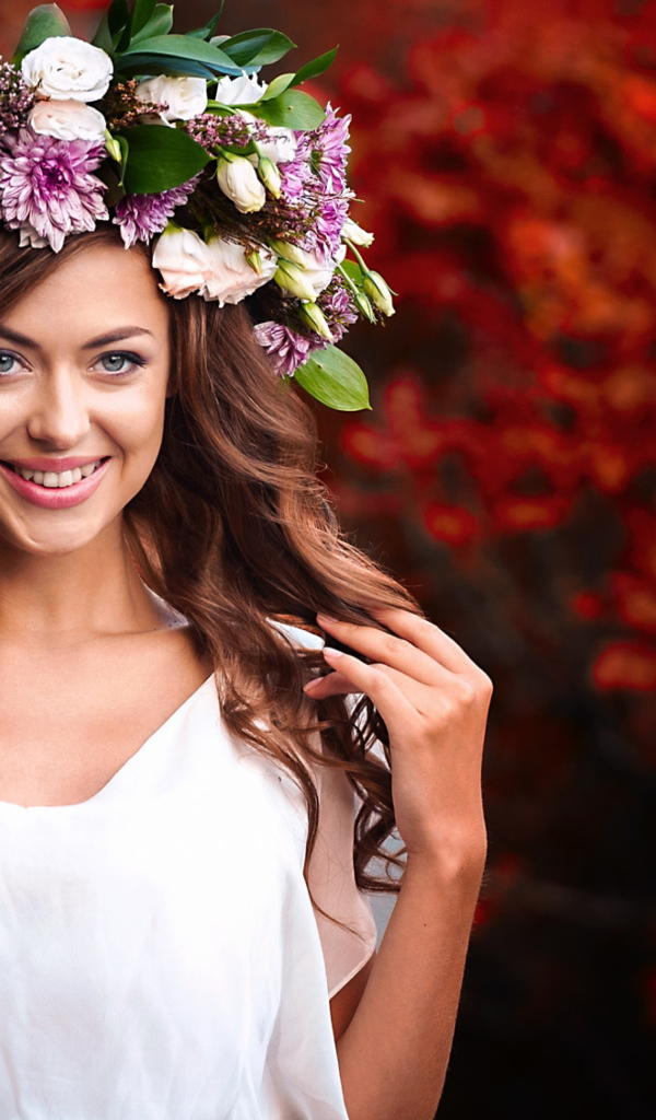 Красивая улыбающаяся девушка с венком из живых цветов на голове 