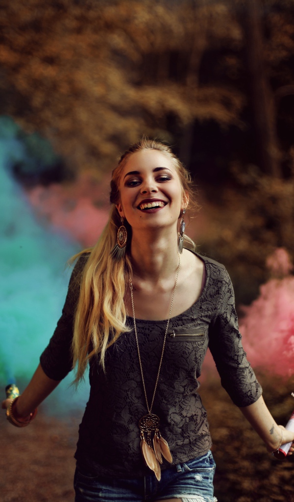 Красивая улыбающаяся девушка с дымовыми шашками в руках