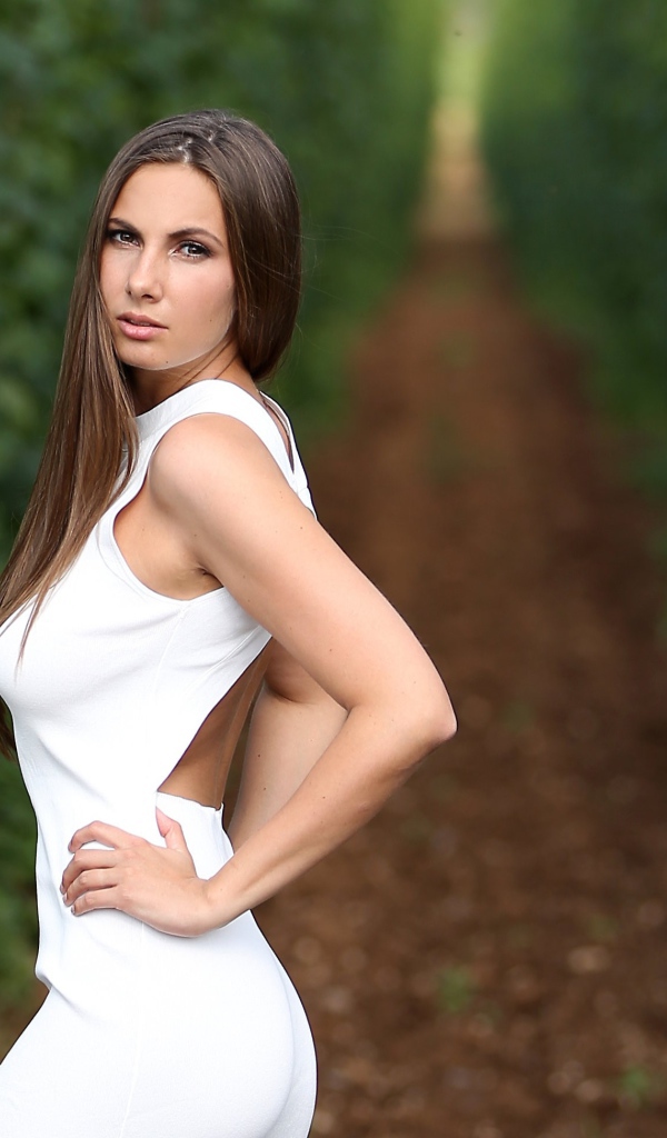 Красивая молодая девушка с длинными волосами в белом платье