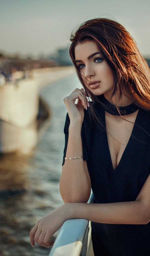 Голубоглазая девушка брюнетка в черном платье у воды 