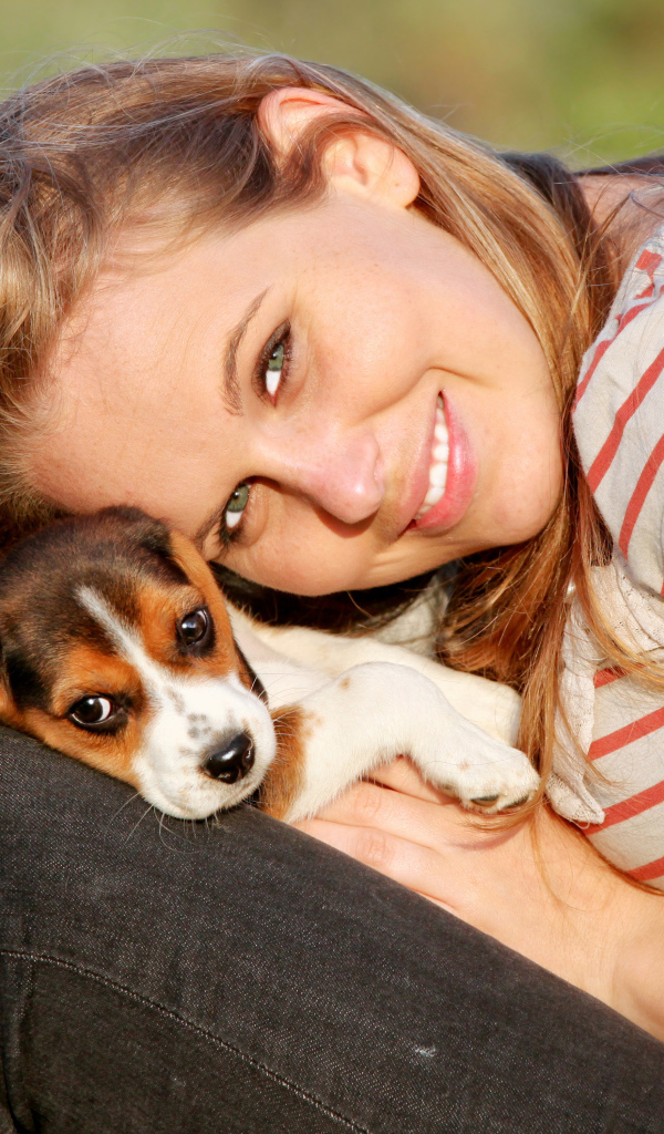 Убающаяся девушка шатенка с милым щенком на руках