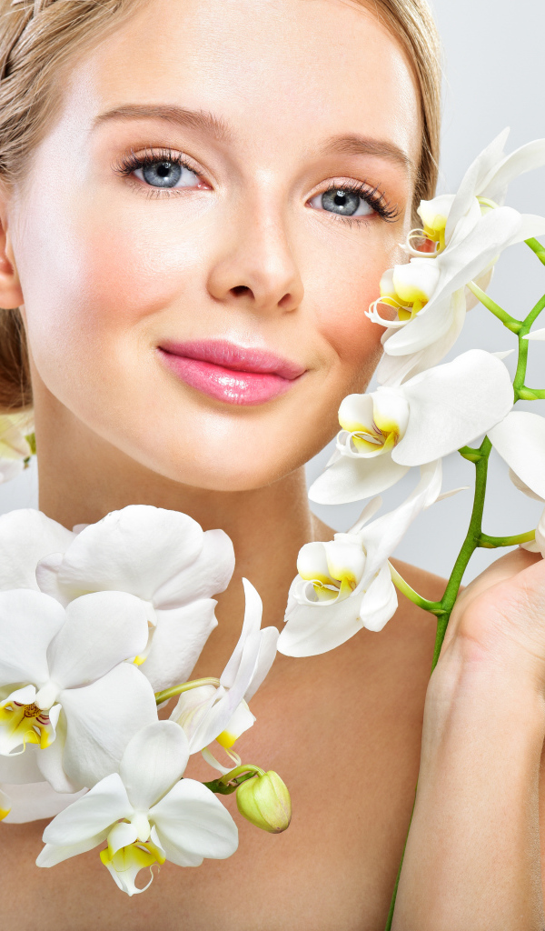 Нежная голубоглазая девушка с цветами орхидеи в руках