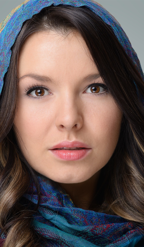 Лицо молодой кареглазой девушки в платке на сером фоне
