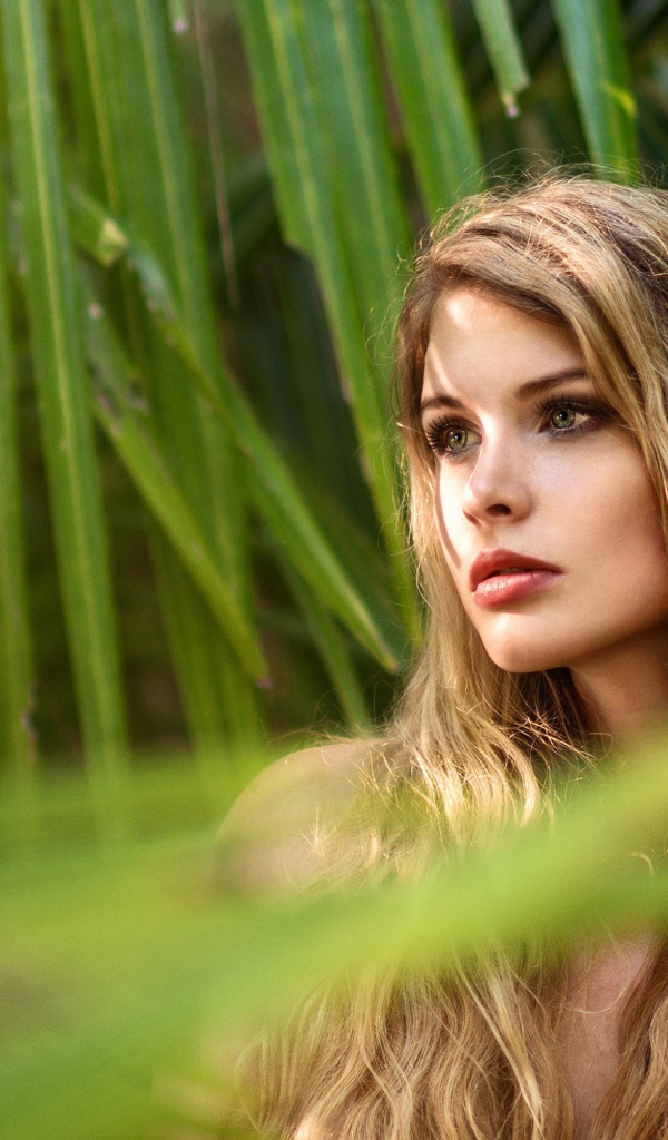 Девушка с волнистыми волосами в пальмовых листьях 