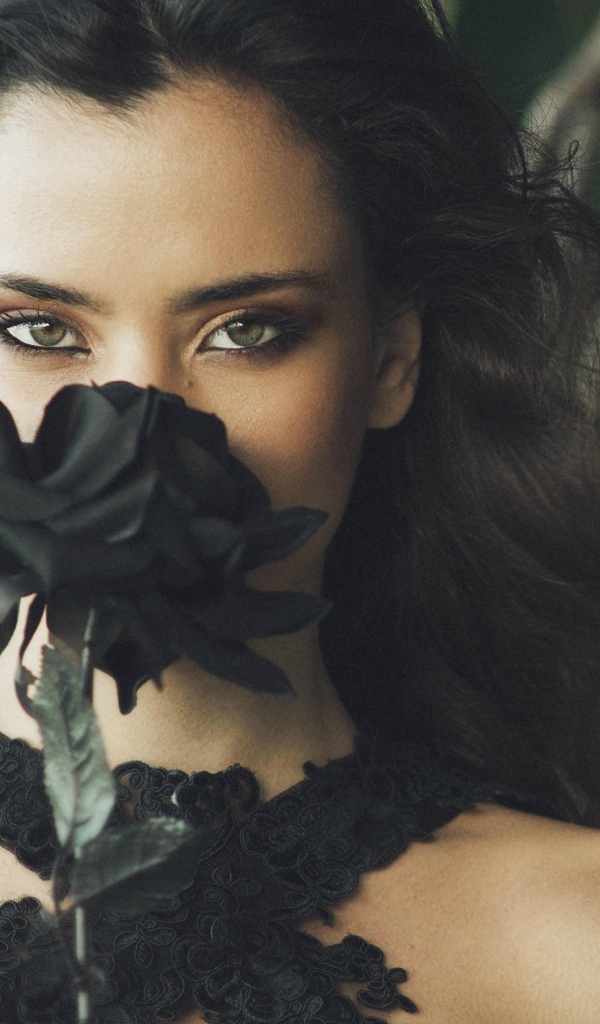 Зеленоглазая девушка брюнетка с черной розой в руках