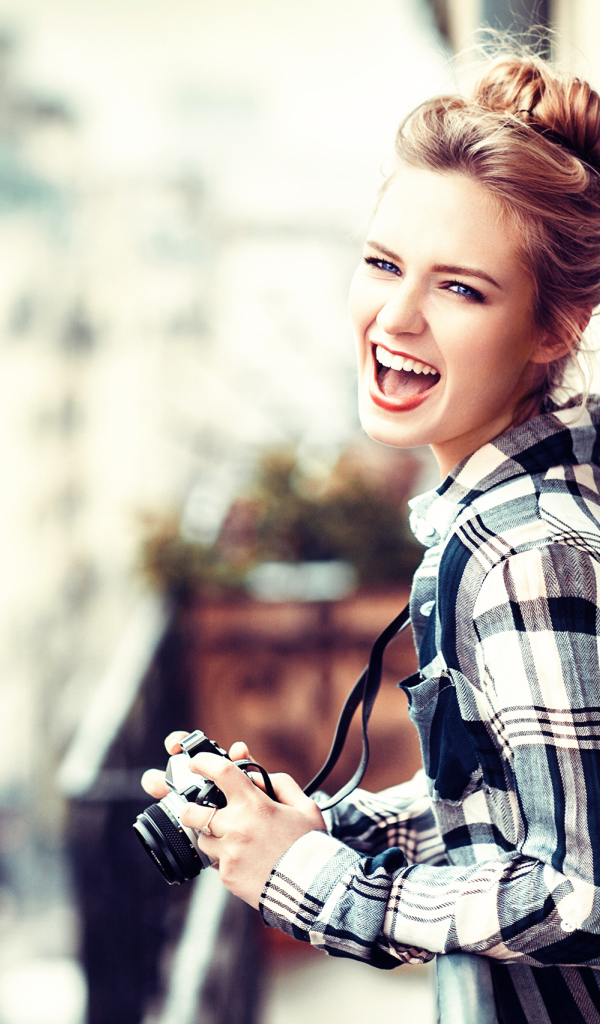 Улыбающаяся девушка в клетчатой рубашке с фотоаппаратом 