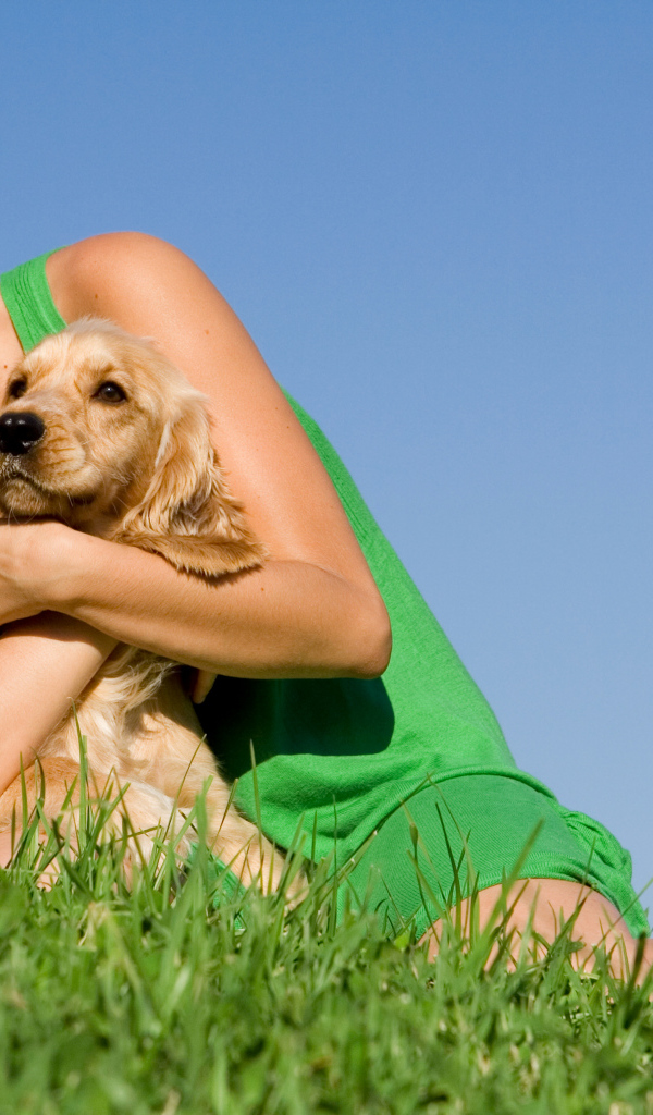 Улыбающаяся девушка со щенком на зеленой траве