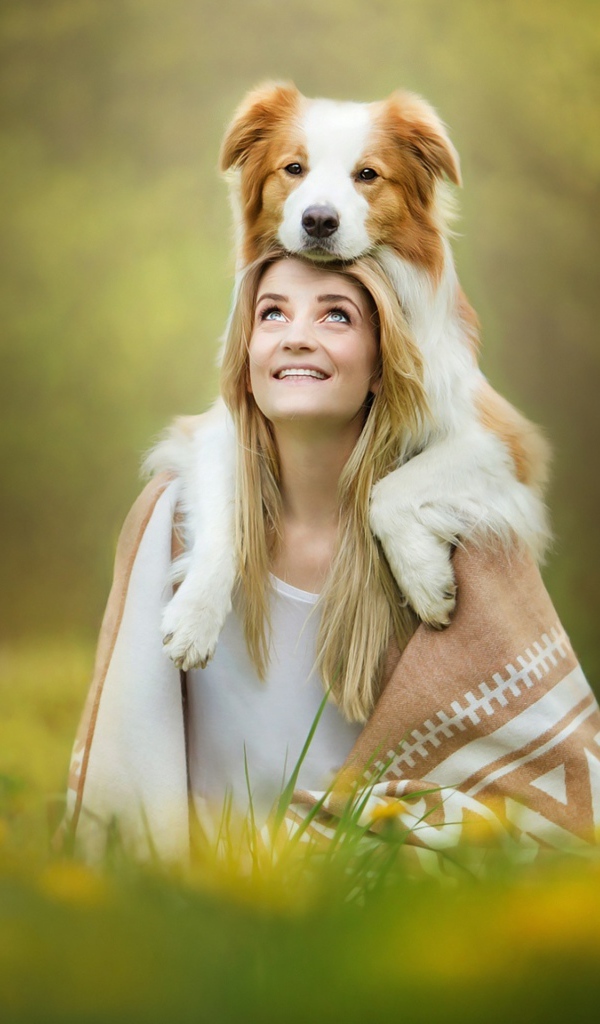 Улыбающаяся девушка с собакой сидят на траве