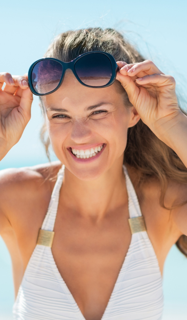 Улыбающаяся девушка с очками на голове