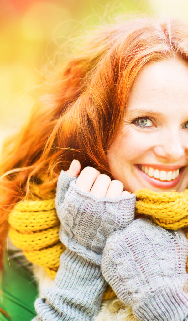 Улыбающаяся рыжеволосая девушка в теплом шарфе