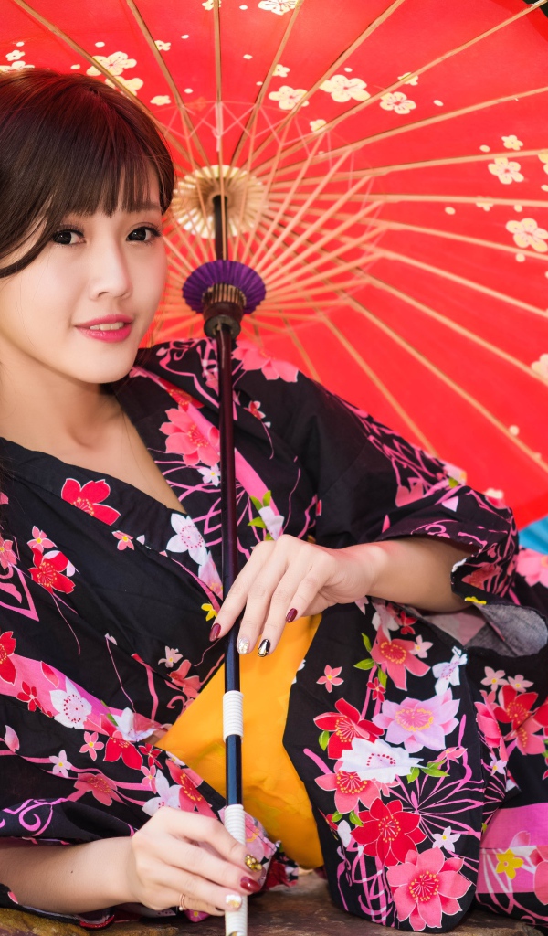 Молодая азиатка в кимоно с разноцветными зонтиками